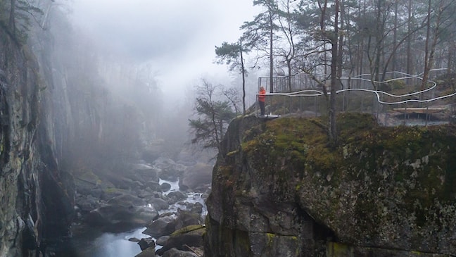 Ei kvinne står og ser utover elv og juv fra et utsiktspunkt.
