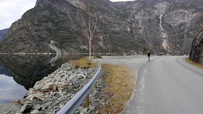 Gruset parkeringslomme tett ved vegen. Utsikt til fjorden.