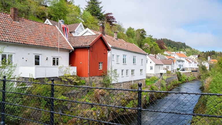 Weiße Holzhäuser entlang des Flusses.